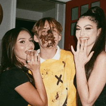 a man with chocolate on his face is standing next to two women and a boy with chocolate on his face .