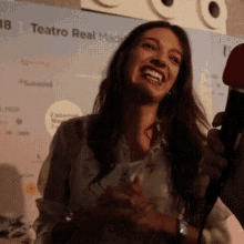 a woman is laughing while being interviewed by a microphone .