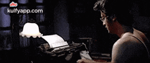 a man is typing on a typewriter in a dark room with a lamp .