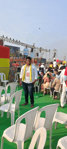 a man with a yellow scarf around his neck stands in front of a crowd