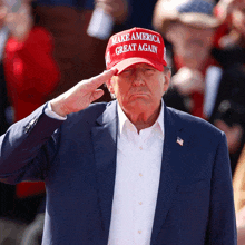 donald trump wearing a red hat that says make america great again salutes