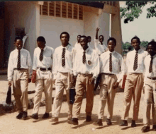 a group of young men wearing shirts and ties are standing in front of a building