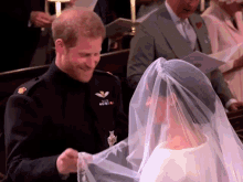 a bride and groom are smiling at each other in a church . the bride is wearing a veil .