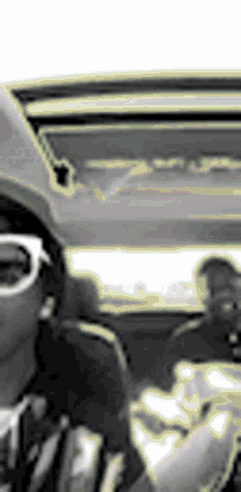 a person wearing sunglasses is sitting in a car .