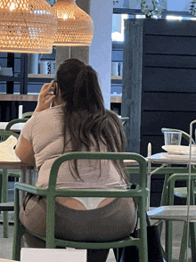 a woman sits in a green chair talking on her phone