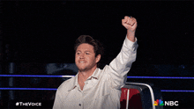 a man in a white shirt holds his fist up in the air in front of a sign that says nbc