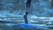 a woman 's foot is walking in the water with a blue light shining on it