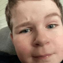 a close up of a young boy 's face with blue eyes and a smile on his face .