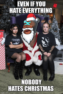 two girls are posing for a picture with santa claus and the caption says even if you hate everything nobody hates christmas