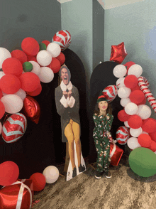 a little girl standing next to a cardboard cutout of a man