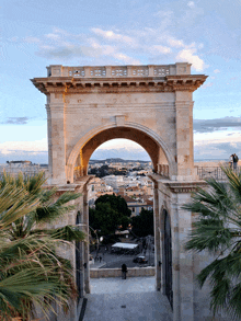 a large stone archway with a view of a city behind it