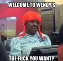 a woman wearing a red wig is sitting at a counter at wendy 's .