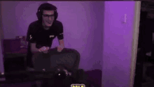 a man wearing headphones and glasses is playing a video game in a dark room .