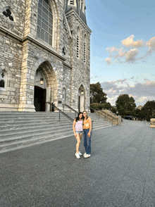 two girls stand in front of a large stone building