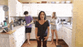 a woman stands in a kitchen with her hands on her hips