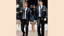 two fbi officers are walking with a cat in their hands .