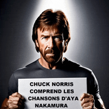 a man holds up a sign that says chuck norris comprend les chansons d'aya nakamura