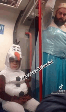 a woman in an aquarius and gemini costume sits next to a man in a frozen costume