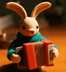 a stuffed bunny is holding an accordion on a table .