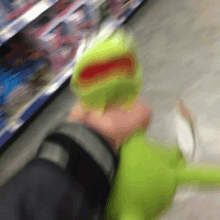 a person is holding a kermit the frog toy in their hand