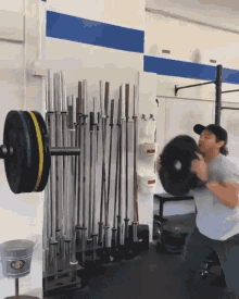 a man is lifting a barbell in a gym with a bucket on the floor that says ' buckets ' on it