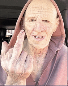 an elderly man in a pink hoodie is giving the middle finger