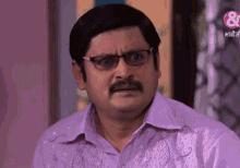 a man with glasses and a mustache is wearing a purple shirt with a pink s on it