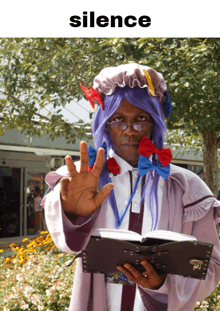 a man with purple hair and glasses is holding a book and making a stop sign under the word silence
