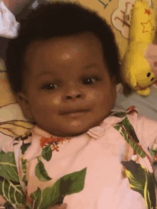 a baby is laying on a bed next to a yellow stuffed animal with a star on it