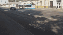 a blue and white bus is driving down a street in front of a building that has the word pharmacy on it