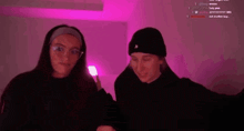 two women are standing next to each other in front of a purple light .