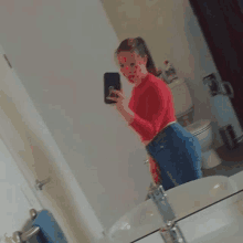 a woman is taking a picture of herself in a bathroom mirror