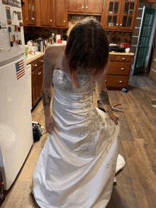 a woman in a wedding dress is kneeling in a kitchen