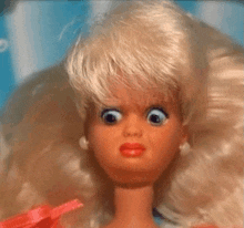 a close up of a barbie doll with big eyes making a funny face