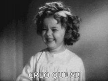 a black and white photo of a little girl laughing with the words `` creo que si '' written below her .