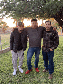 three men posing for a picture with one wearing a jacket that says reebok on it