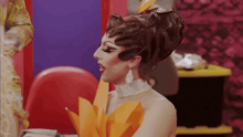 a drag queen wearing a costume with a flower on her head