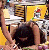 a woman is sitting at a table with her head down in front of a sign that says damian toyo