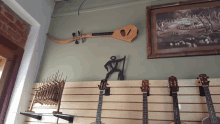 several guitars are displayed on a wall with a picture on the wall above them