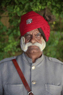 a man wearing a red turban with a lion emblem