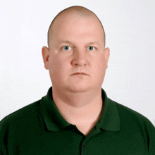 a man wearing a green polo shirt looks at the camera