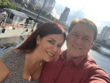 a man and a woman are posing for a selfie in front of a city skyline