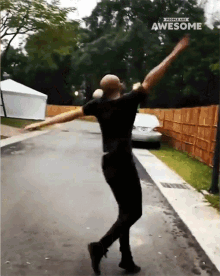 a man in a black shirt is dancing in front of a sign that says " people are awesome "