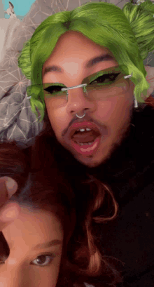 a man with green hair and glasses is making a face with a woman