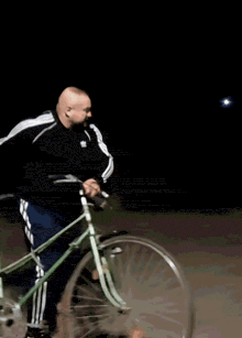 a man in a black and white adidas jacket is riding a scooter at night