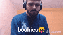 a man wearing headphones and a shirt that says boobies on it