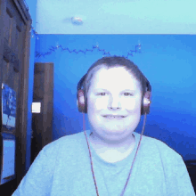 a young boy wearing headphones against a blue wall