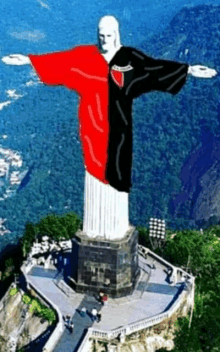 a statue of jesus wearing a red and black shirt with the word jesus on it