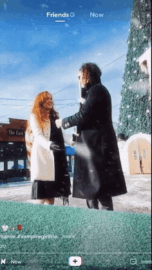 a man and a woman standing in front of a christmas tree .