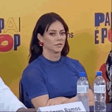 a woman is sitting at a table with bottles of water .